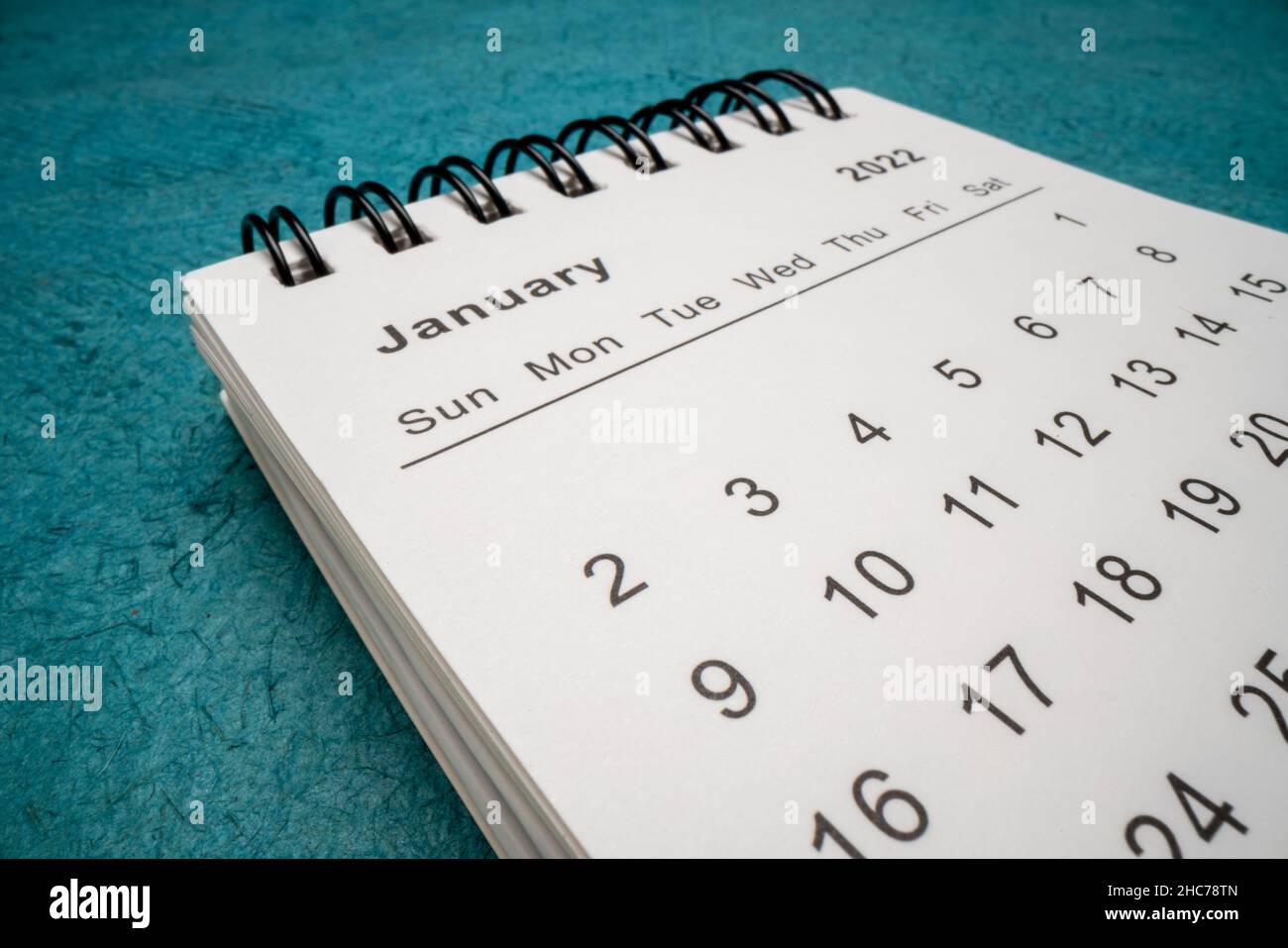 Gennaio 2022 - calendario desktop a spirale contro carta texture blu, Capodanno, concetto di tempo e business, macro shot dal punto di vista dell'obiettivo della sonda Foto Stock