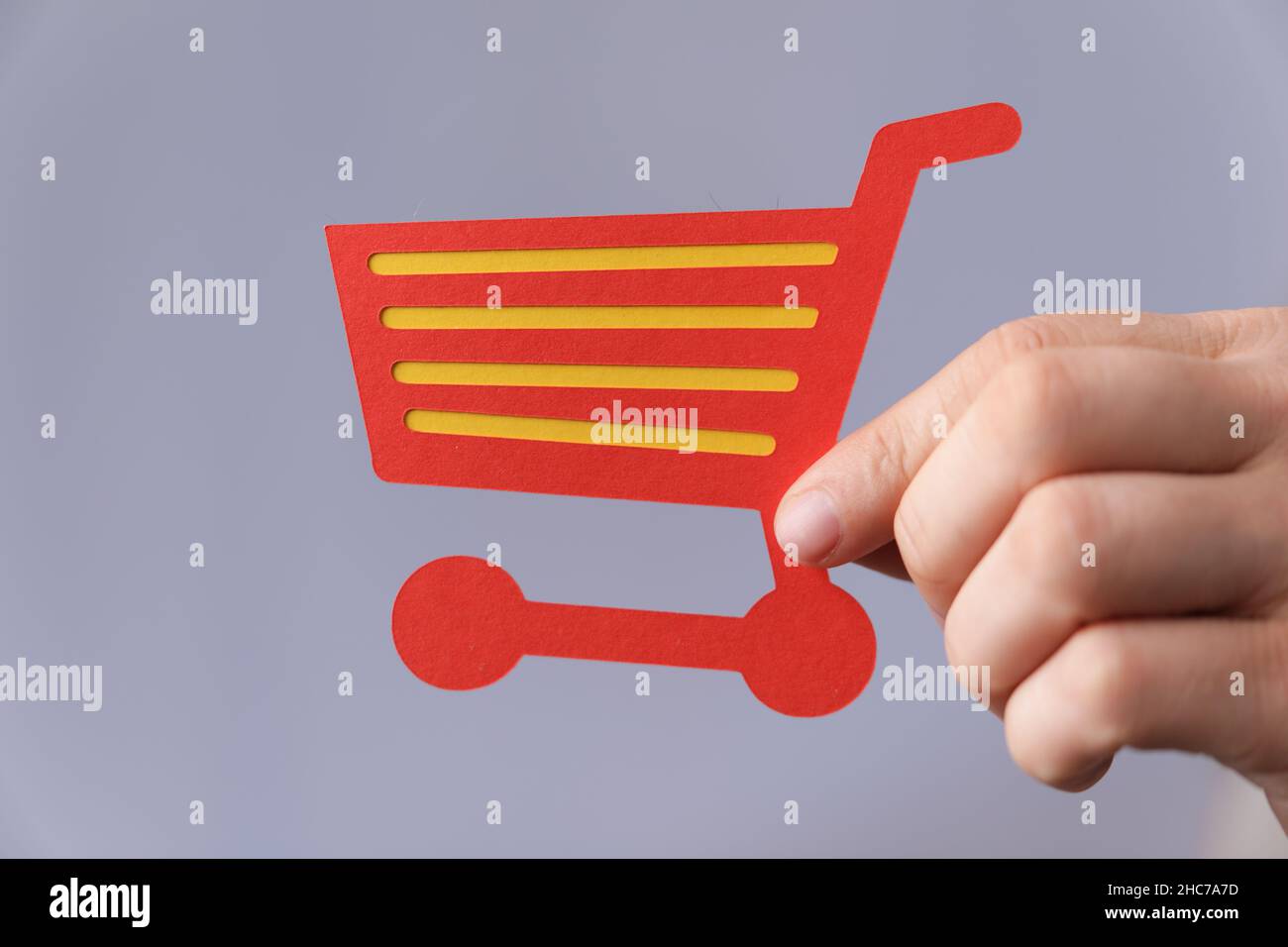 Primo piano di una mano maschile che tiene un'icona carrello acquisti su uno sfondo digitale di acquisto Foto Stock