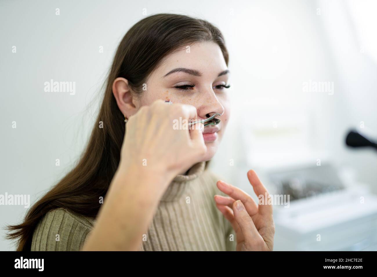Il medico di ENT femminile esamina i seni del paziente con lo strumento medico nella clinica moderna. Otorhinolaryngologist controlla il naso della ragazza del paziente per Foto Stock