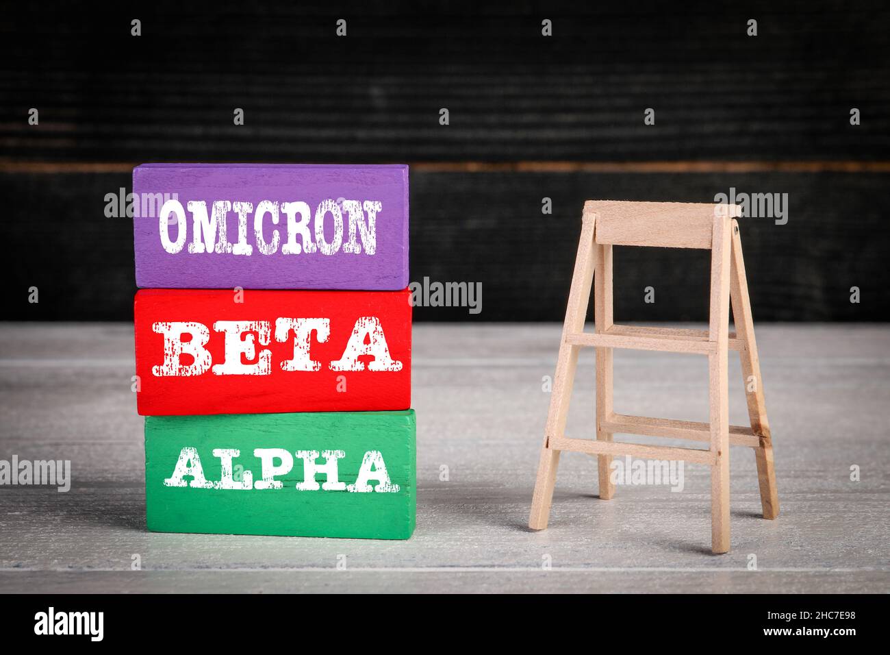 VIRUS OMICRON BETA ALFA Covid-19. Blocchi di legno colorati in un palo e scale. Foto Stock