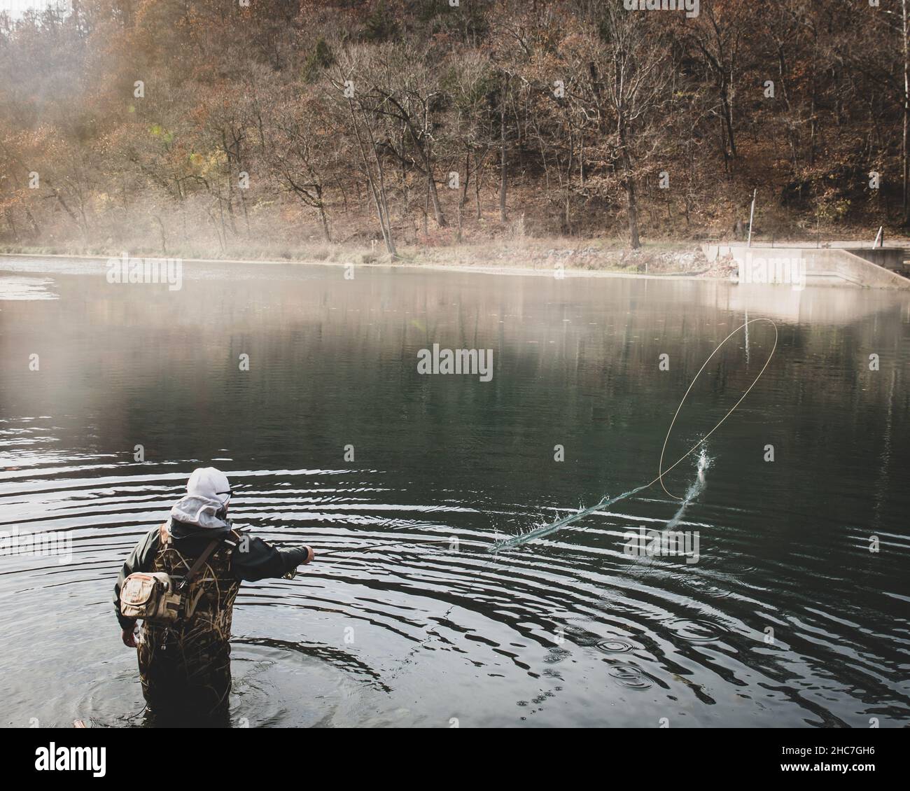 Luminosa mattinata autunnale con una persona che pesca alla trota in un lago in Missouri, USA Foto Stock