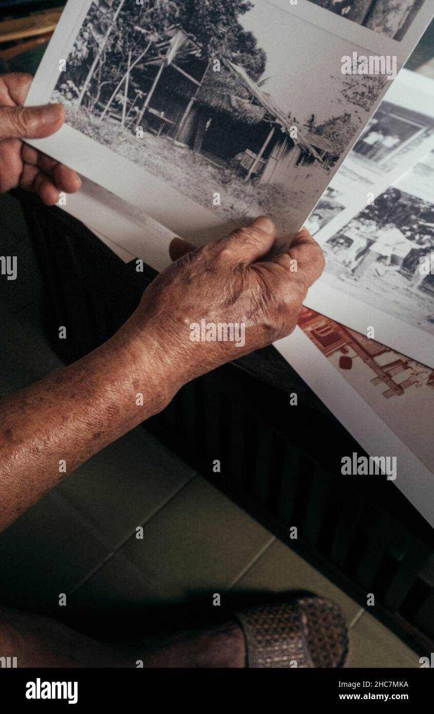 vecchie mani asiatiche maschili che tengono su foto in bianco e nero di paglia casa Foto Stock