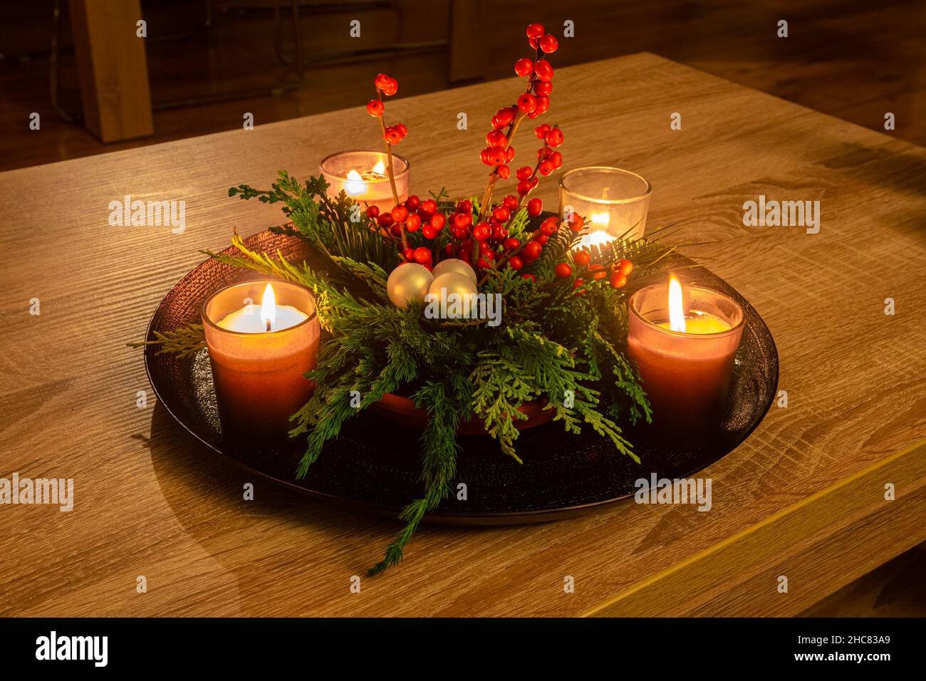 Decorazioni natalizie fatte a mano con candele, rami di conifere e bacche rosse Foto Stock