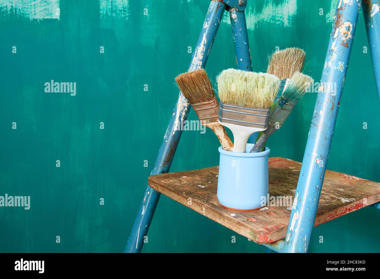 Sfondo verde con spazio per il testo. Le spazzole nel vaso si trovano su una scala a cavalletto. Spazio di copia Foto Stock