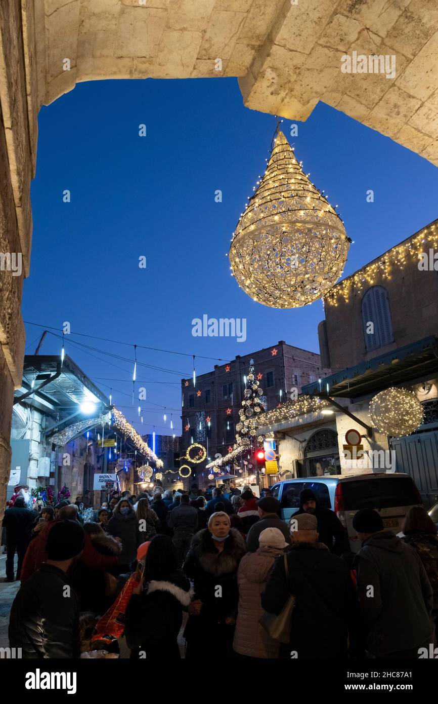 Gerusalemme, Israele. 25th Dic 2021. La gente cammina lungo una strada decorata a Natale Bab el Gadid nel quartiere cristiano della città vecchia il 25 dicembre 2021 a Gerusalemme, Israele. Gli israeliani hanno limitato a viaggiare all'estero, a causa dell'impennata della variante Omicron COVID-19, che riempiva i vicoli a tema natalizio del quartiere cristiano. Credit: Eddie Gerald/Alamy Live News Foto Stock