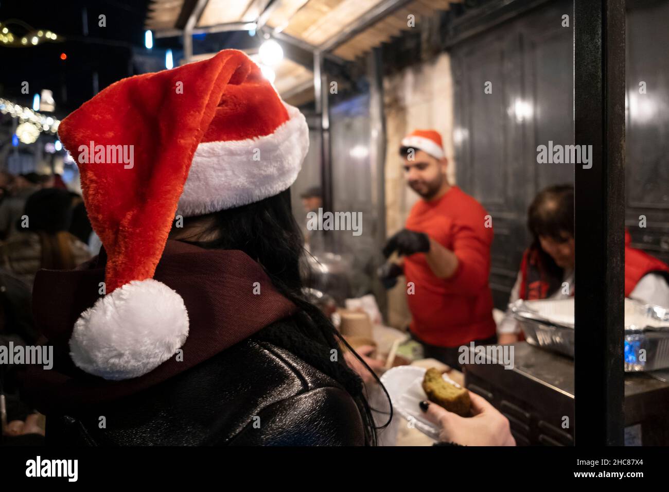 Gerusalemme, Israele. 25th Dic 2021. La gente compra il cibo tradizionale di Natale lungo la via di Bab el Gadid nel quartiere cristiano della città vecchia il 25 dicembre 2021 a Gerusalemme, Israele. Gli israeliani hanno limitato a viaggiare all'estero, a causa dell'impennata della variante Omicron COVID-19, che riempiva i vicoli a tema natalizio del quartiere cristiano. Credit: Eddie Gerald/Alamy Live News Foto Stock