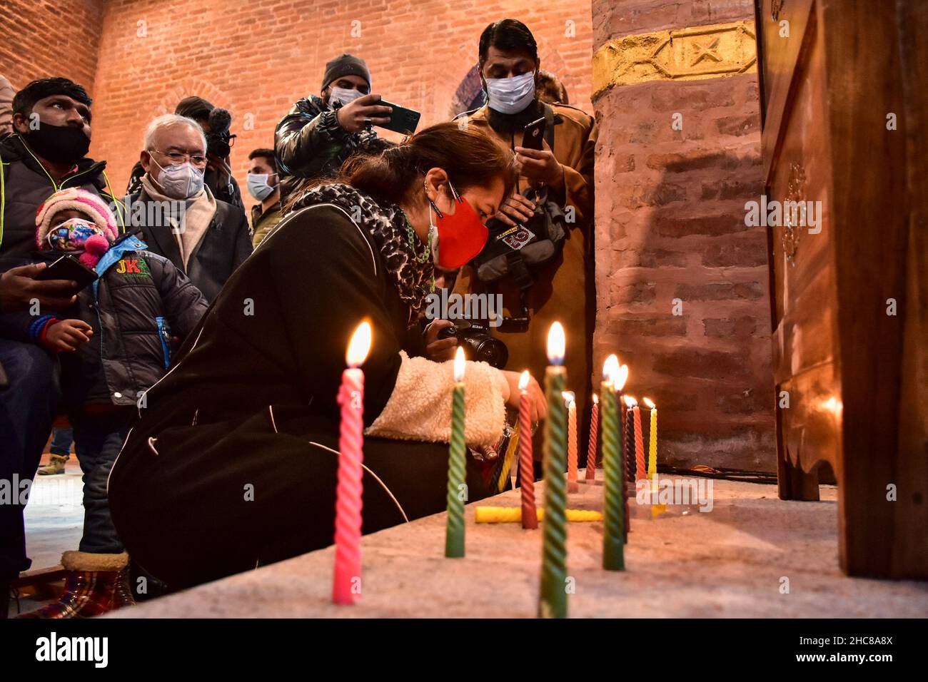 Srinagar, India. 25th Dic 2021. Un devoto cristiano accende le candele all'interno della chiesa di San Lukes il giorno di Natale a Srinagar.dopo tre decenni, la chiesa di San Luca di 125 anni, rimasta desolata a seguito della crescente violenza nel 1990s, è stata rinnovata e aperta per i fedeli il Natale. I cristiani in India e in tutto il mondo celebrano il Natale per commemorare la nascita di Gesù, figura centrale del cristianesimo. Credit: SOPA Images Limited/Alamy Live News Foto Stock