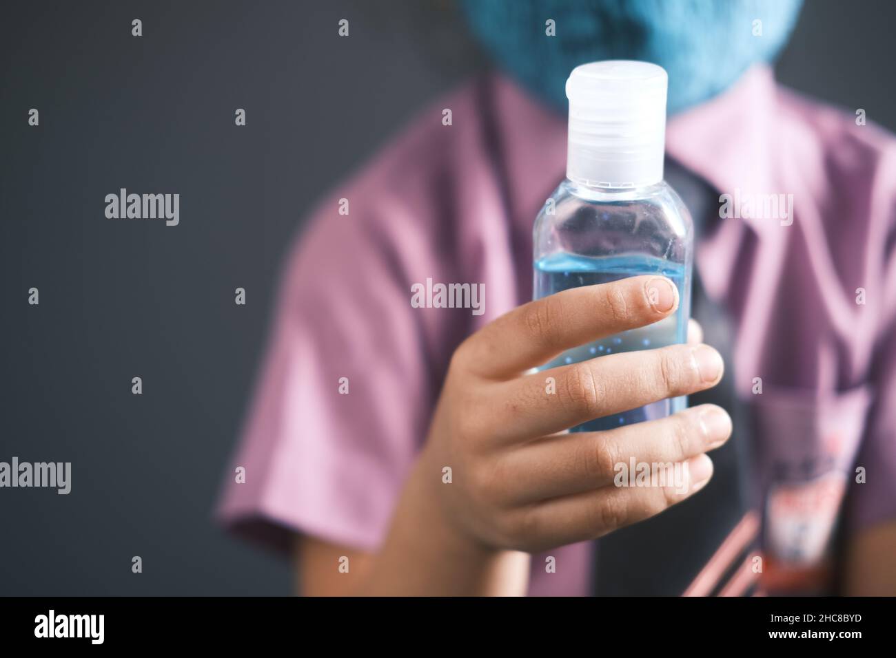 bambina in abito a scuola che tiene igienizzatore a mano con spazio copia Foto Stock