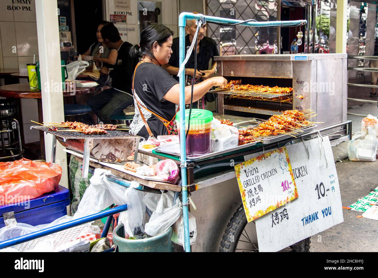 Vendita di pollo alla griglia di Street food a Soi Cowboy - famosa via go go bar, Sukhumvit, Bangkok, Thailandia Foto Stock