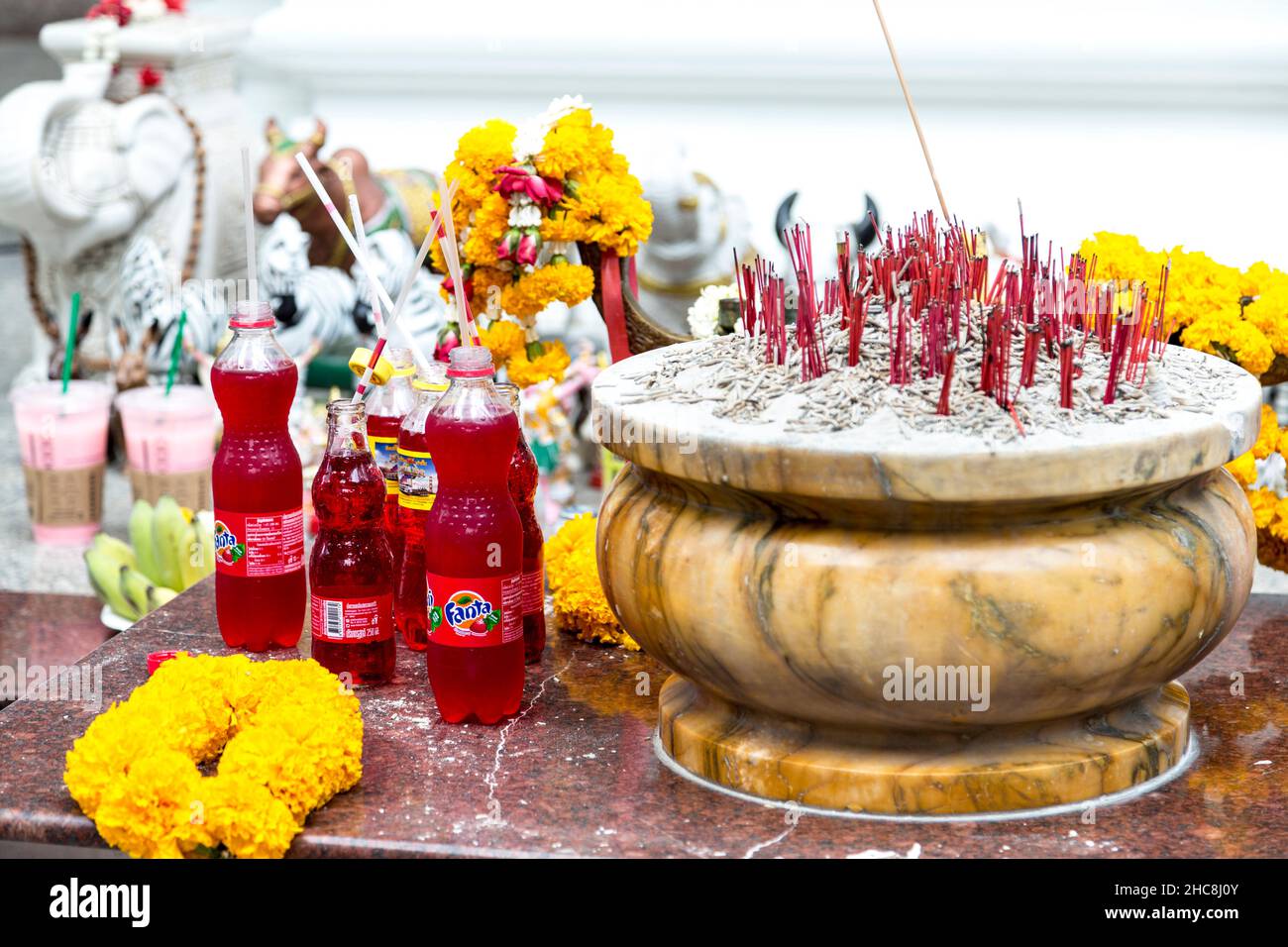 Offerte e regali, bevande, bottiglie e incenso ardente al Santuario di Ardhanari fuori dalla Torre della Citta' di Jasmine, Sukhumvit Road, Bangkok, Tailandia Foto Stock