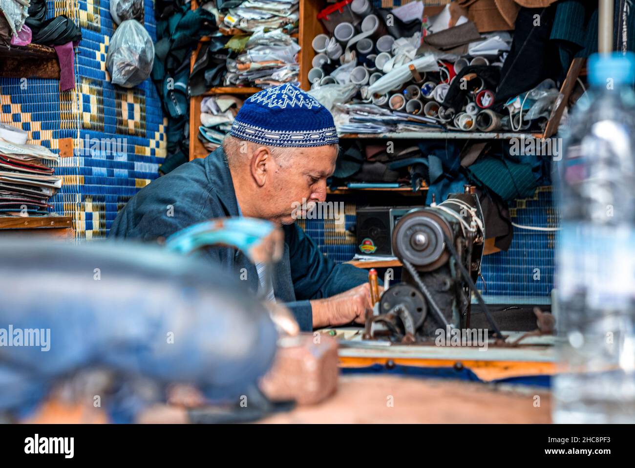 Uomo su misura in cappellino di preghiera blu cucito con macchina da cucire in negozio Foto Stock