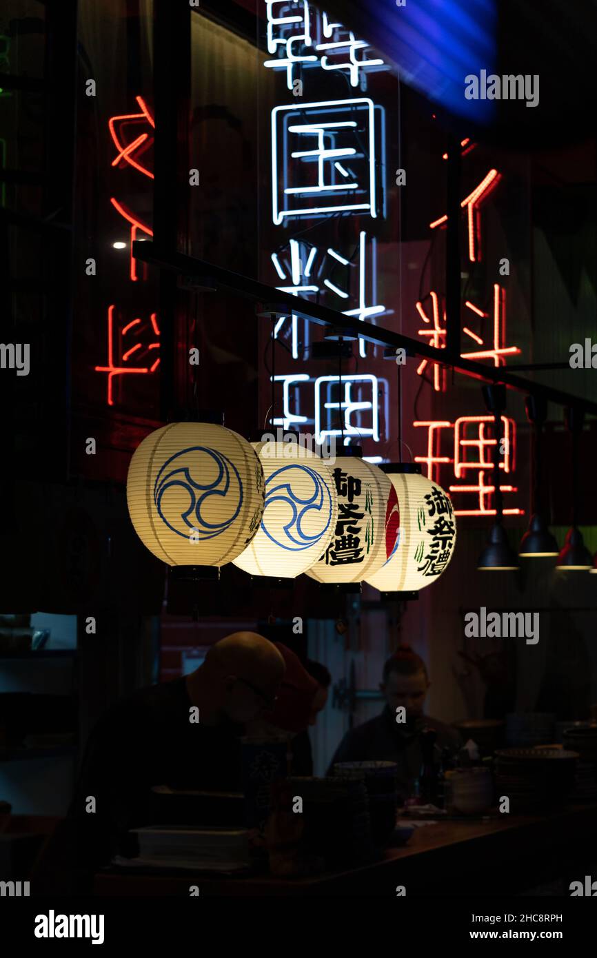 Interni del ristorante Cinese con caratteri cinesi al neon e decorazioni in lanterne di carta sulle pareti Foto Stock