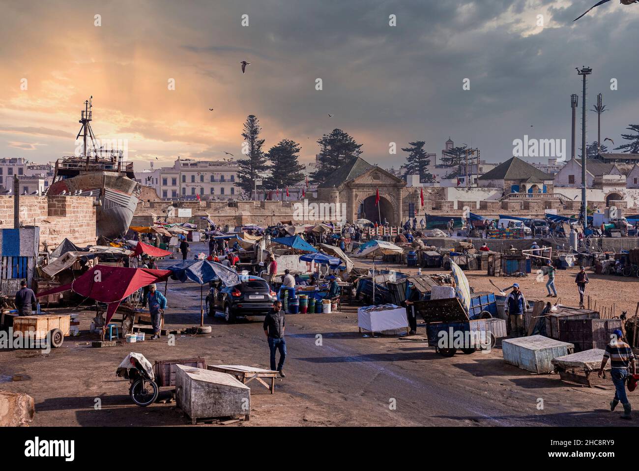 La gente cammina intorno al mercato del pesce accanto al muro circostante al porto turistico Foto Stock