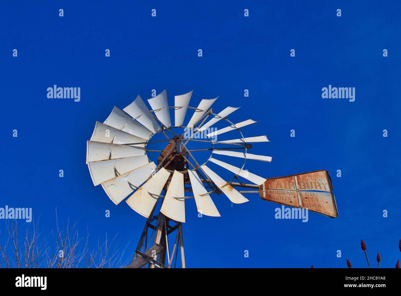 Colpo ad angolo basso di un vecchio mulino a vento arrugginito su uno sfondo blu cielo senza nuvole Foto Stock