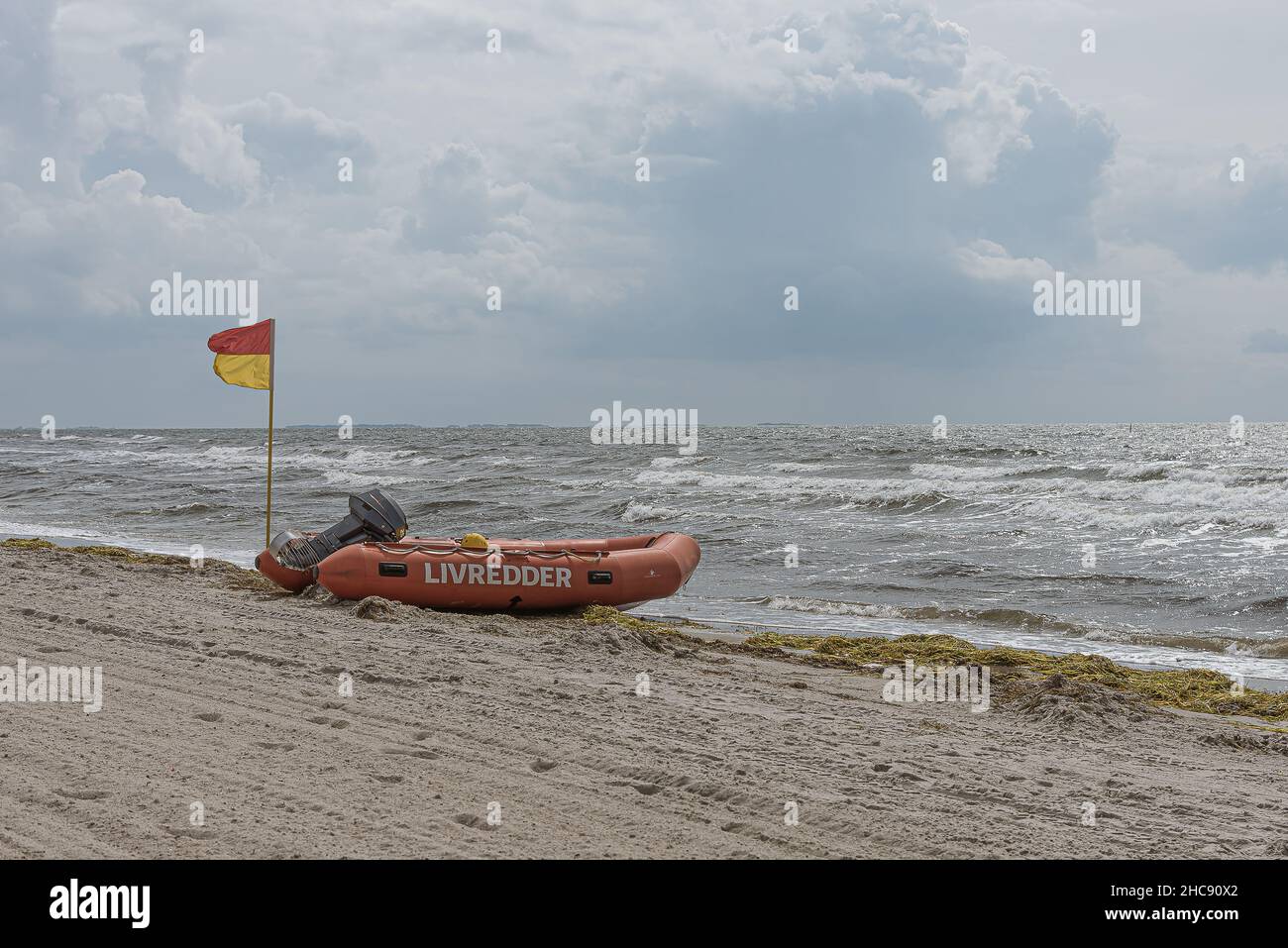 Gommone e bandiera rossa e gialla su una spiaggia che significa che ha bagnino supervisione, Karrebæksminde, Danimarca, 9 agosto 2021 Foto Stock
