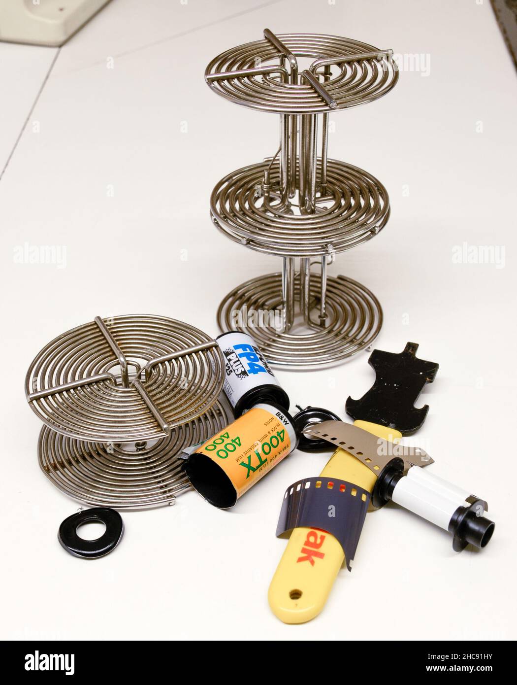 Spirali per la lavorazione di pellicole, apparecchiature tradizionali per lo sviluppo di metalli e cassette per pellicole aperte con uno strumento di apertura. spirali da 35 mm e 120 mm. Foto Stock