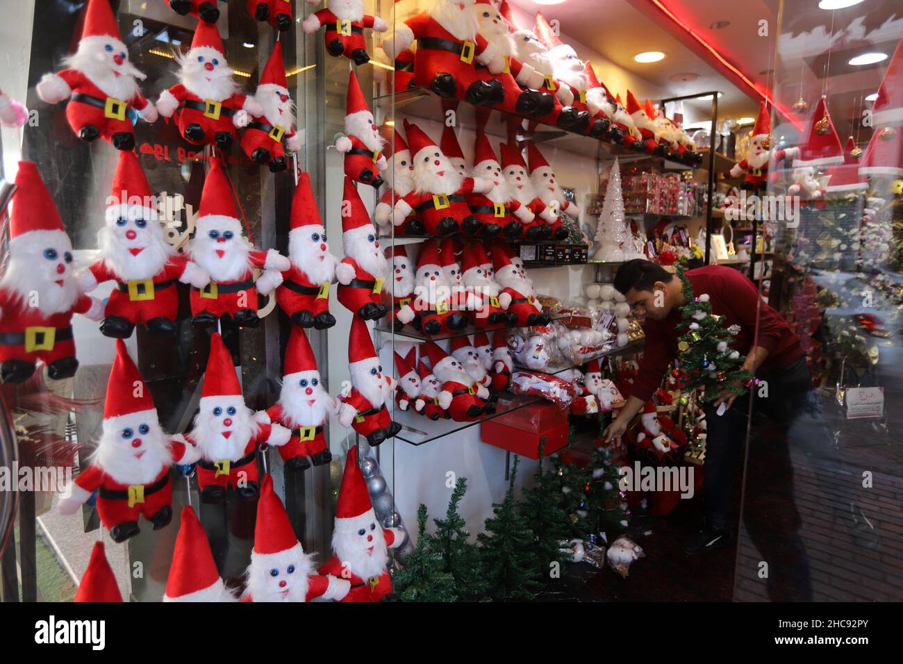 Gaza, Palestina. 26th Dic 2021. Un venditore palestinese mostra bambole di Babbo Natale al suo negozio di articoli da regalo la vigilia di Natale a Gaza City.i negozi di articoli da regalo e ristoranti si stanno preparando nella striscia di Gaza per celebrare il Natale decorando i loro ristoranti e mostrando regali nei loro negozi come bambole di Babbo Natale e piccoli alberi di Natale luminosi. (Foto di Ahmed Zakot/SOPA Images/Sipa USA) Credit: Sipa USA/Alamy Live News Foto Stock