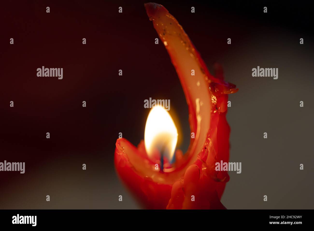 macro fotografia di una candela di cera rossa consumata dalla sua fiamma calda Foto Stock