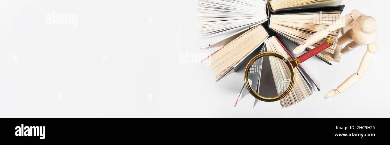 Lente di ingrandimento sopra il libro di carta aperto. Concetto di conoscenza, ricerca e studio. Banner con spazio di copia. Foto Stock