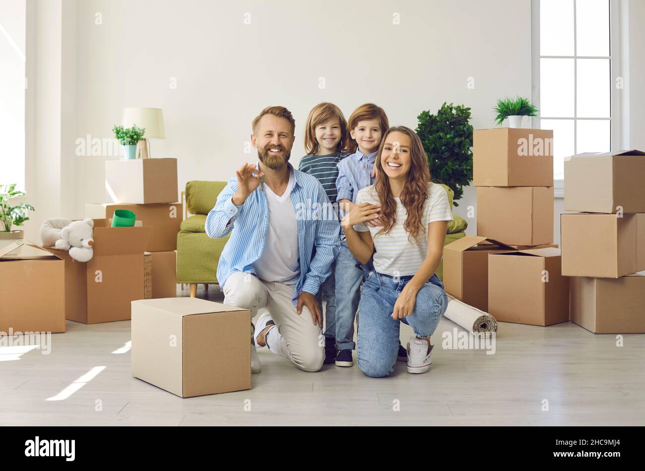 Famiglia felice sorridendo e mostrando le chiavi per la loro casa o appartamento appena comprato Foto Stock