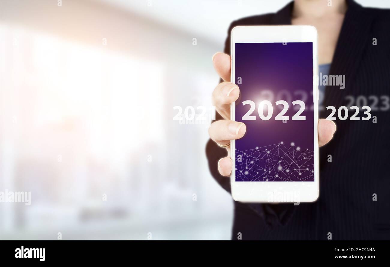 Anno di carico dal 2021 al 2022. Inizia concetto. Smartphone bianco con hologram digitale 2022 su sfondo sfocato chiaro. Felice anno nuovo 2022 Foto Stock
