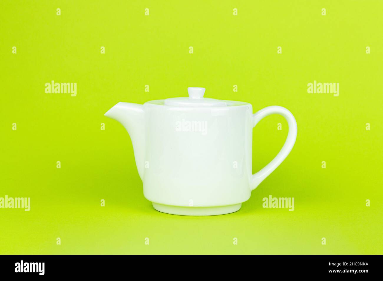 Teiera in ceramica bianca su sfondo verde. Concetto di tè con teiera bianca. Foto Stock