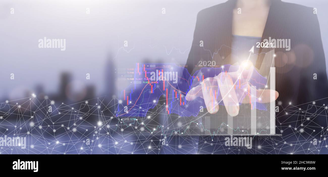Concetto di crescita aziendale anno 2021. Mano touch schermo digitale ologramma crescita grafico segno grafico sulla città luce sfondo sfocato. Grafico che mostra il guadagno Foto Stock