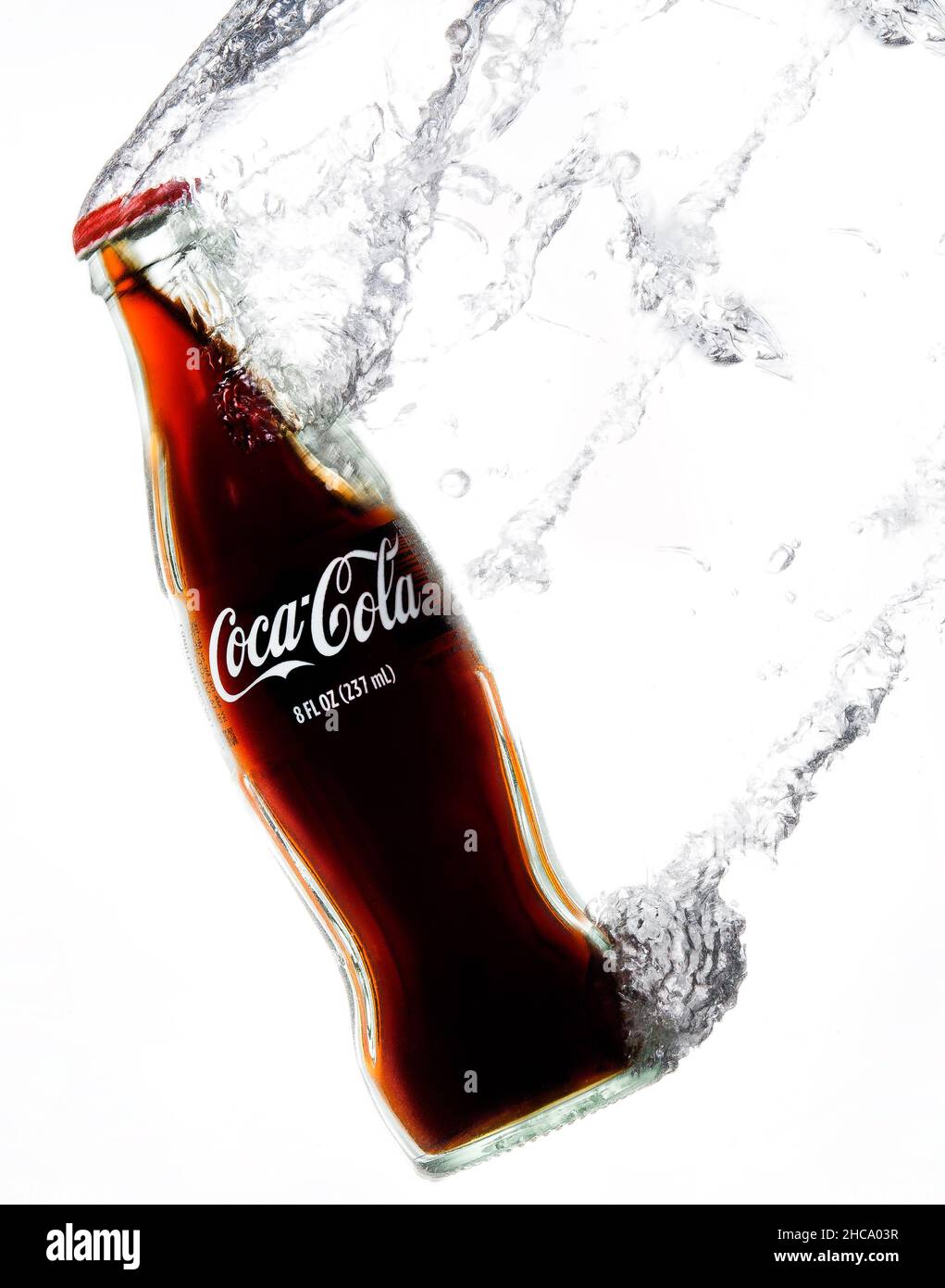 Closeup verticale della classica bottiglia di Coca-Cola che si gonfio sotto l'acqua lasciando una scia di bollicine. Foto Stock