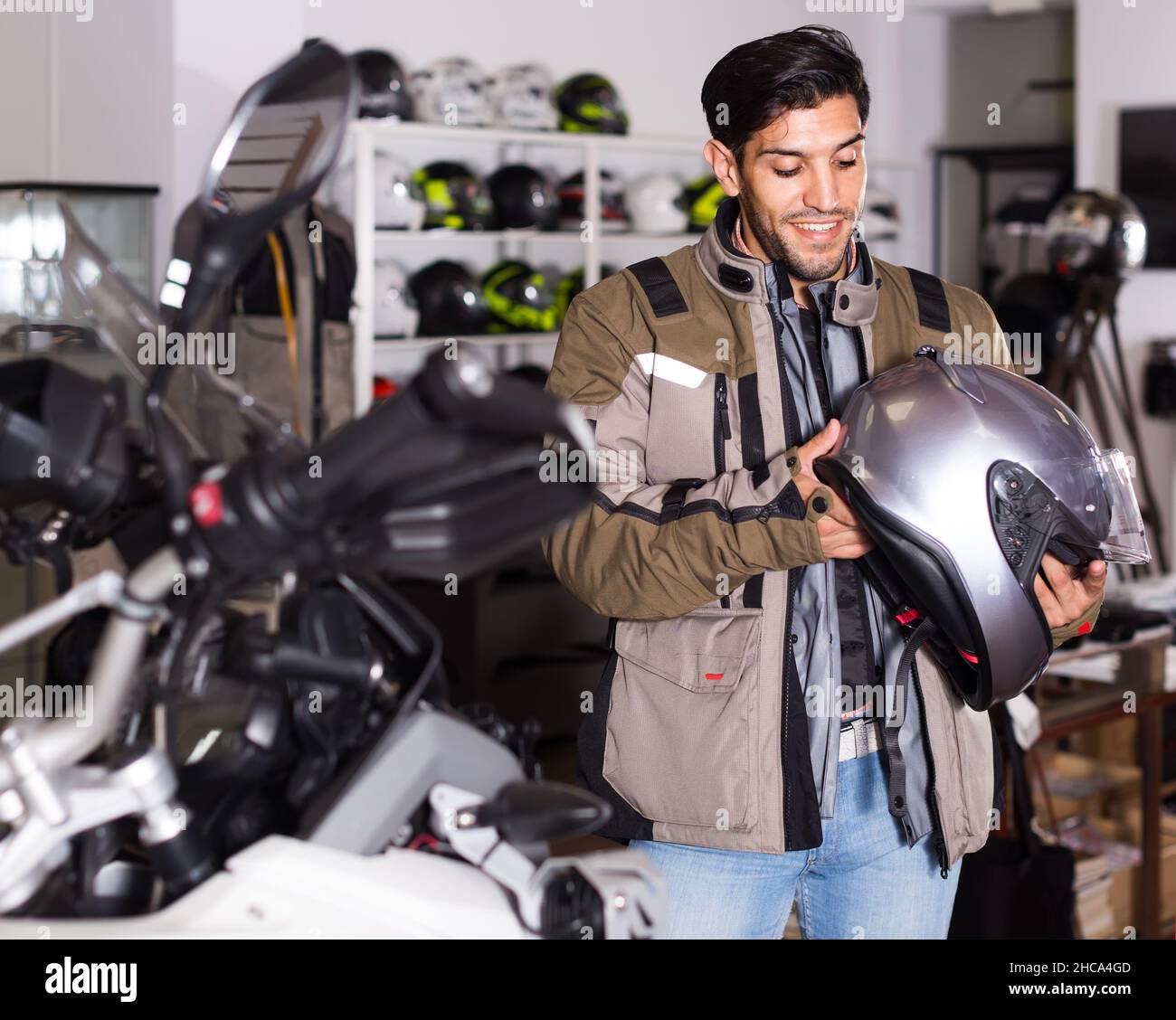 Uomo in giacca moto sta scegliendo il nuovo casco per moto nel negozio Foto  stock - Alamy