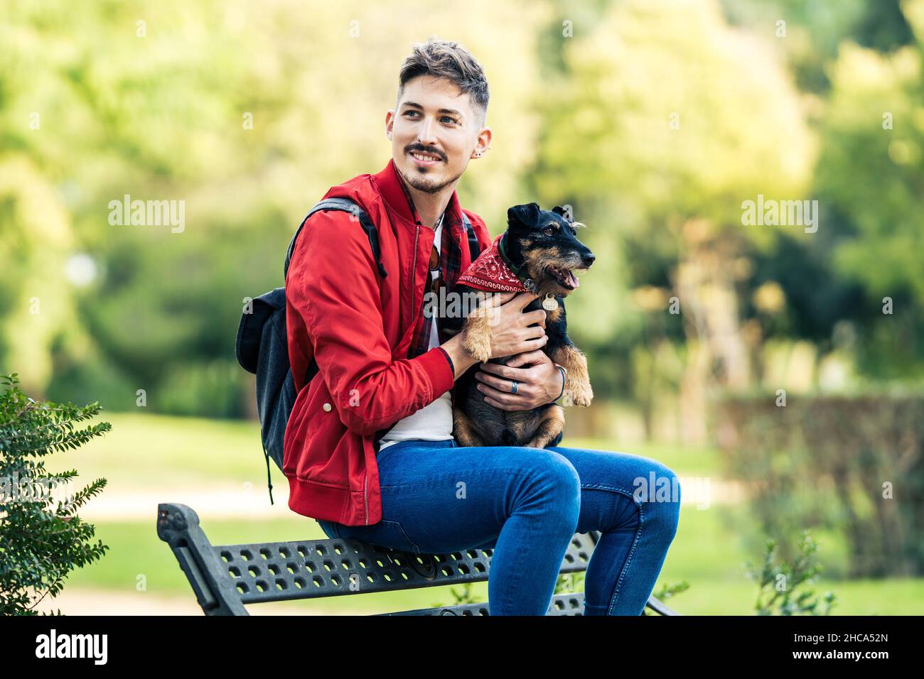 Uomo distratto che tiene un cane mentre si siede su una panca in un parco Foto Stock