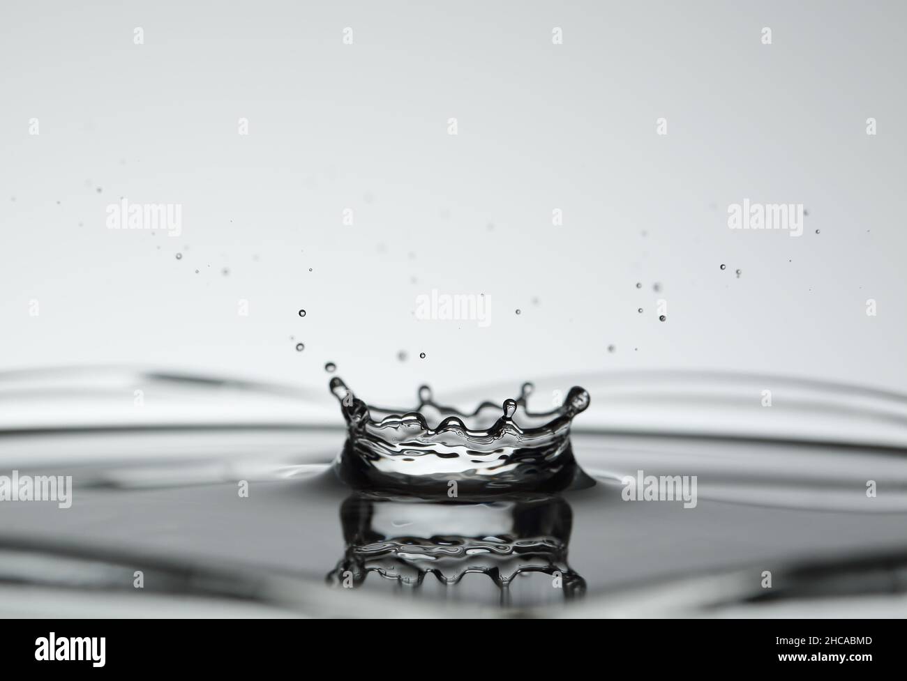 Spruzzi d'acqua che fanno forma di corona su sfondo luminoso Foto Stock