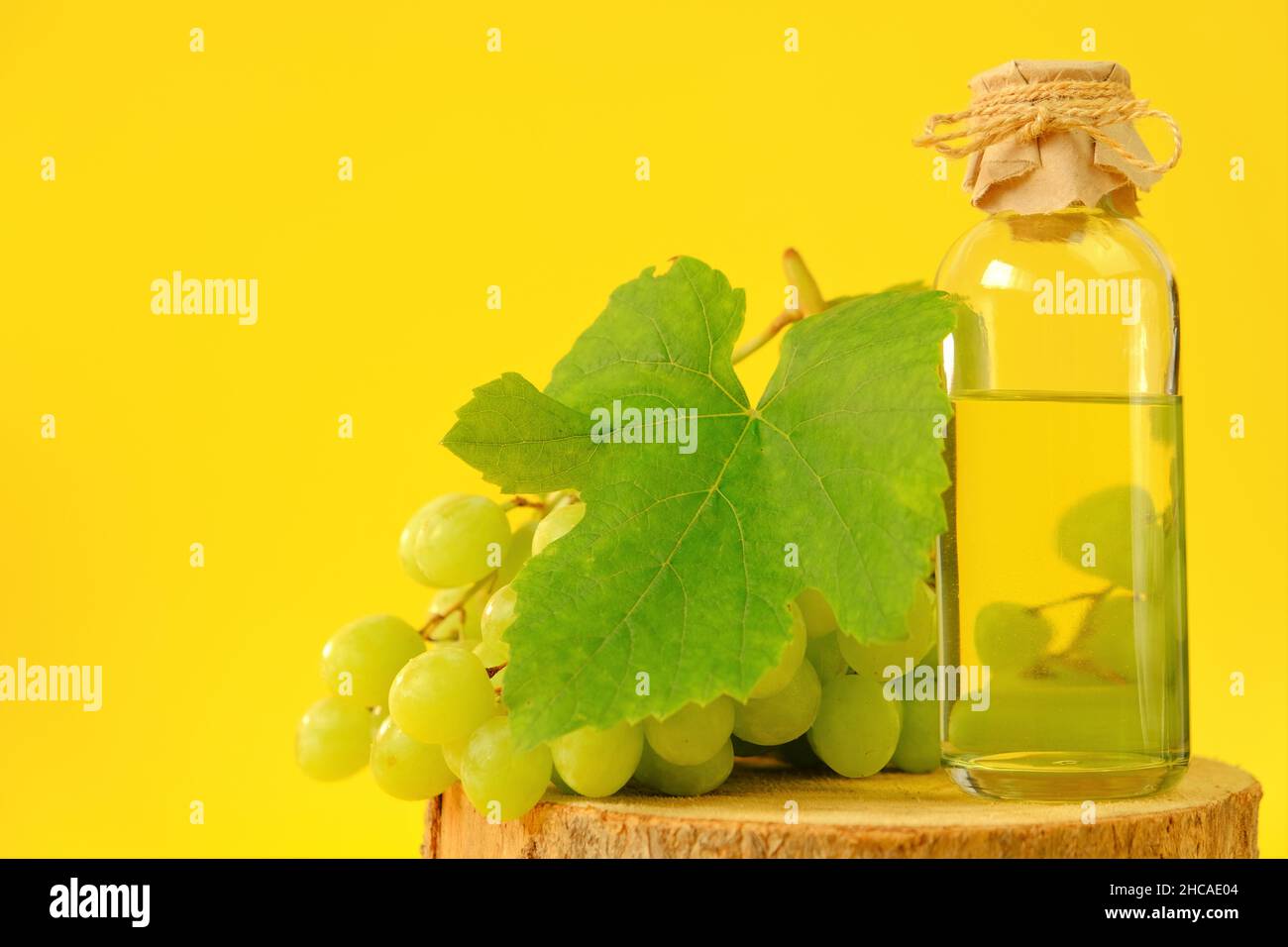 Olio di semi di uva. Olio cosmetico base per massaggio viso e corpo. Bottiglia e mazzo di uve verdi Foto Stock