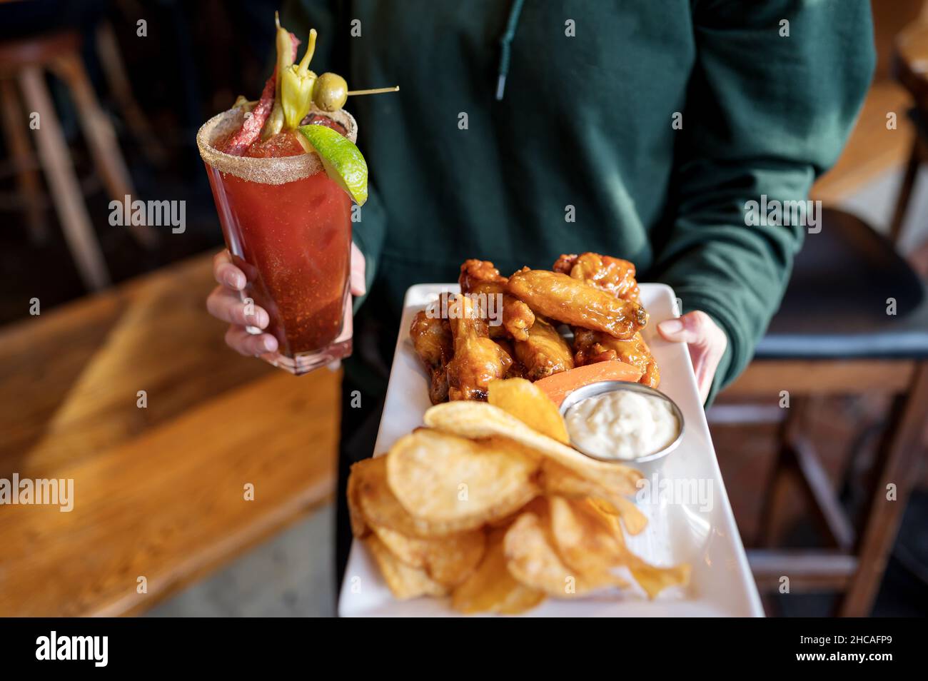 Un piatto di ali di pollo con patatine e un cocktail Caesar canadese. Foto Stock