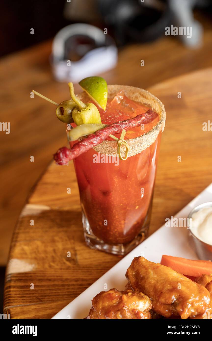 Un piatto di ali di pollo con patatine e un cocktail Caesar canadese. Foto Stock