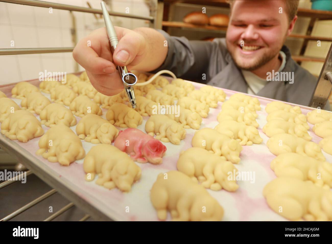 Wernigerode, Germania. 23rd Dic 2021. L'apprendista pasticceria Leon Mathews lavora su fortunati maiali marzapane presso la pasticceria Silberbach. La pasticceria produce centinaia di fortunati maialini marzapane per la vigilia di Capodanno come fascino fortunato per i suoi clienti. Credit: dpa/dpa-Zentralbild/ZB/dpa/Alamy Live News Foto Stock