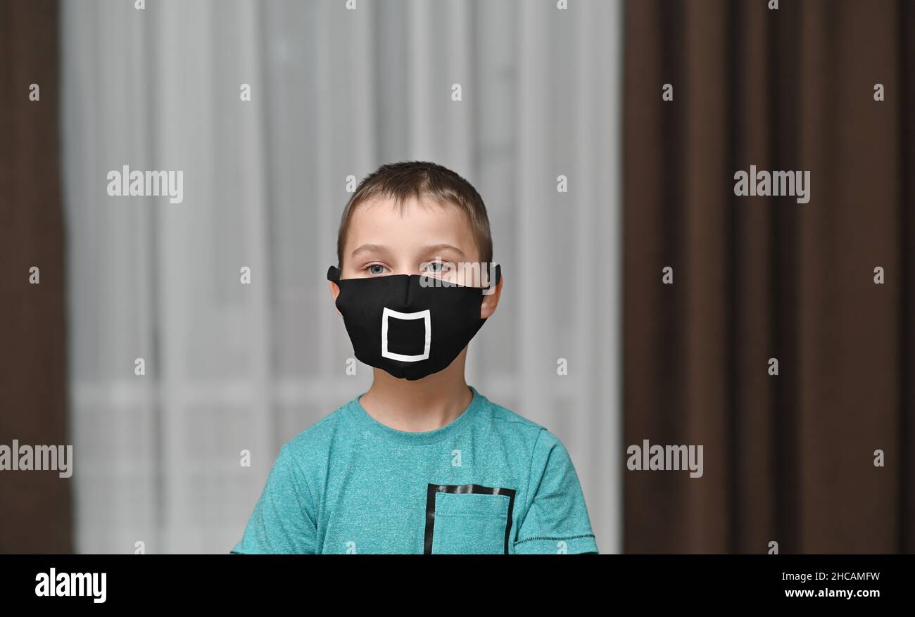 ragazzo in una maschera protettiva. un quadrato bianco su una maschera nera. Foto Stock