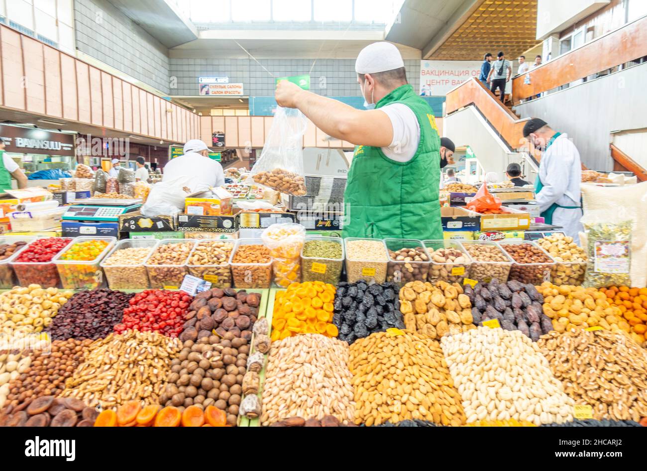 Un uomo che vende frutta secca e noci al mercato verde bazar bazar, il più grande e più antico mercato al coperto di Almaty, Kazakhstan Foto Stock