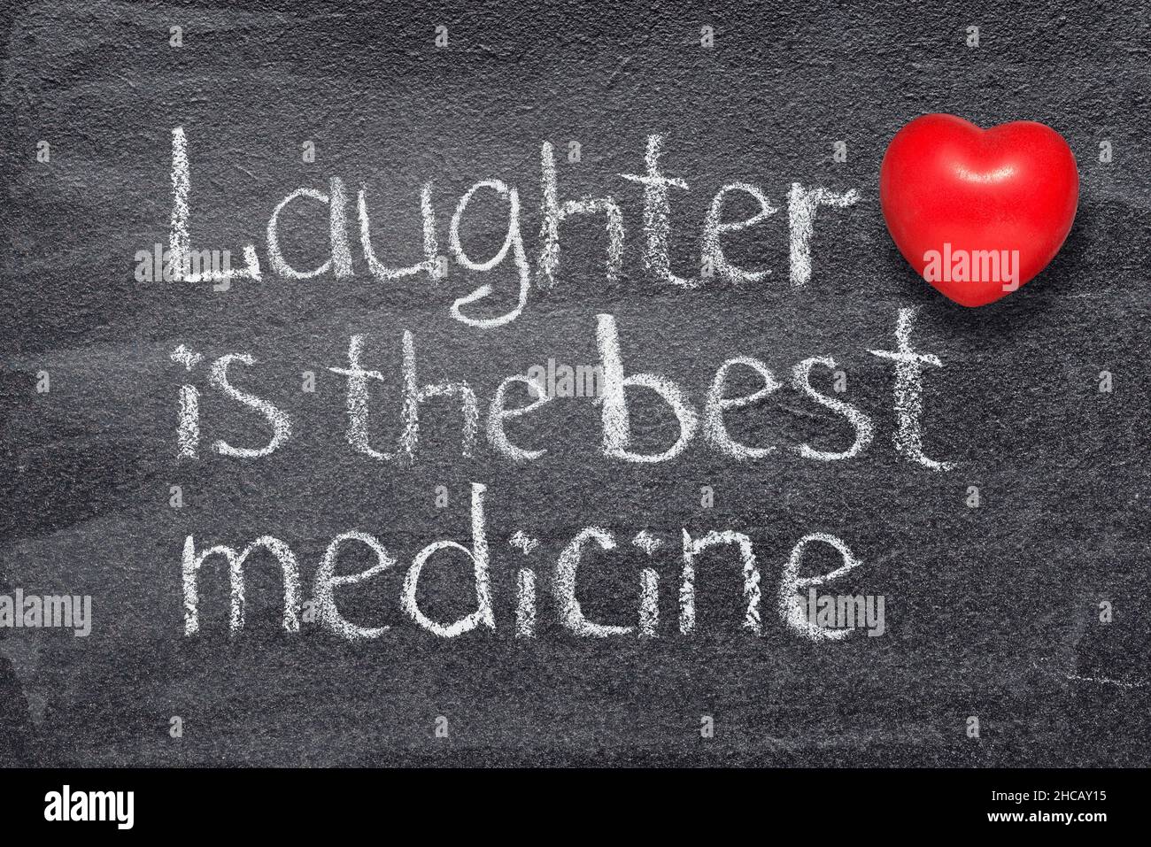 La risata è il migliore proverbio della medicina scritto sulla lavagna con il simbolo del cuore rosso Foto Stock