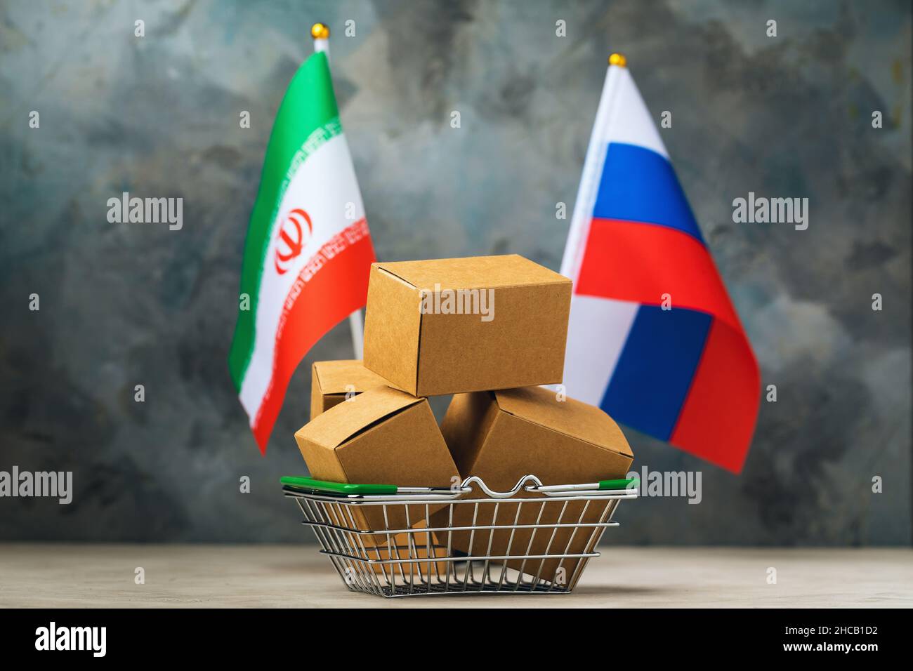 Varie scatole in un paniere alimentare e due bandiere su un background astratto, il concetto di commercio tra Iran e Russia Foto Stock