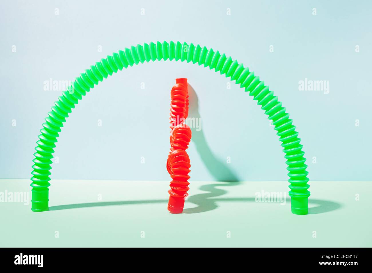 Il tubo pop curvo è appoggiato contro la parete. Vita morta moderna con giocattolo antistress. Foto Stock