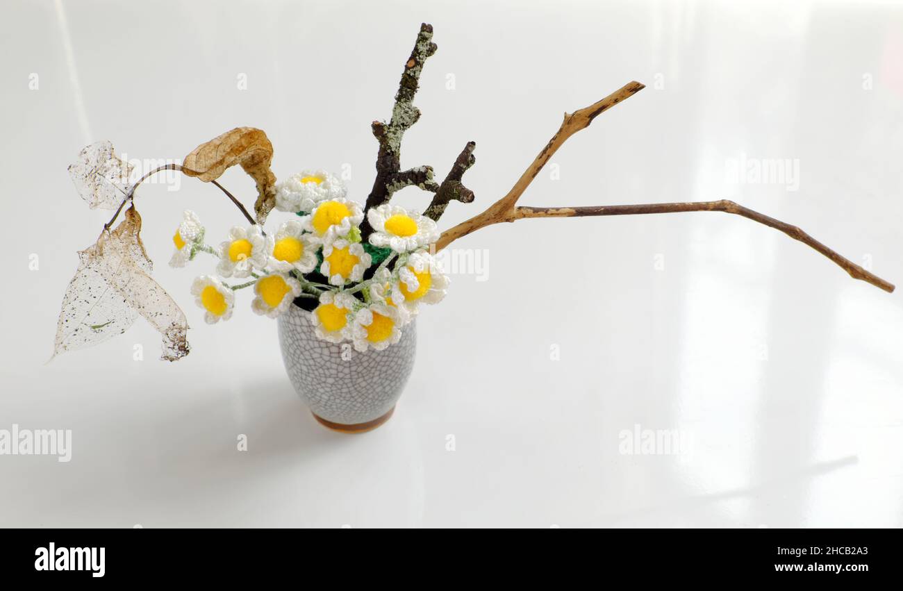 Vaso Daisy per arredamento casa, vaso fiore diy da riciclare maschera viso con cemento bianco, crochet piccolo fiore bianco con pistil giallo e ramo secco di albero Foto Stock