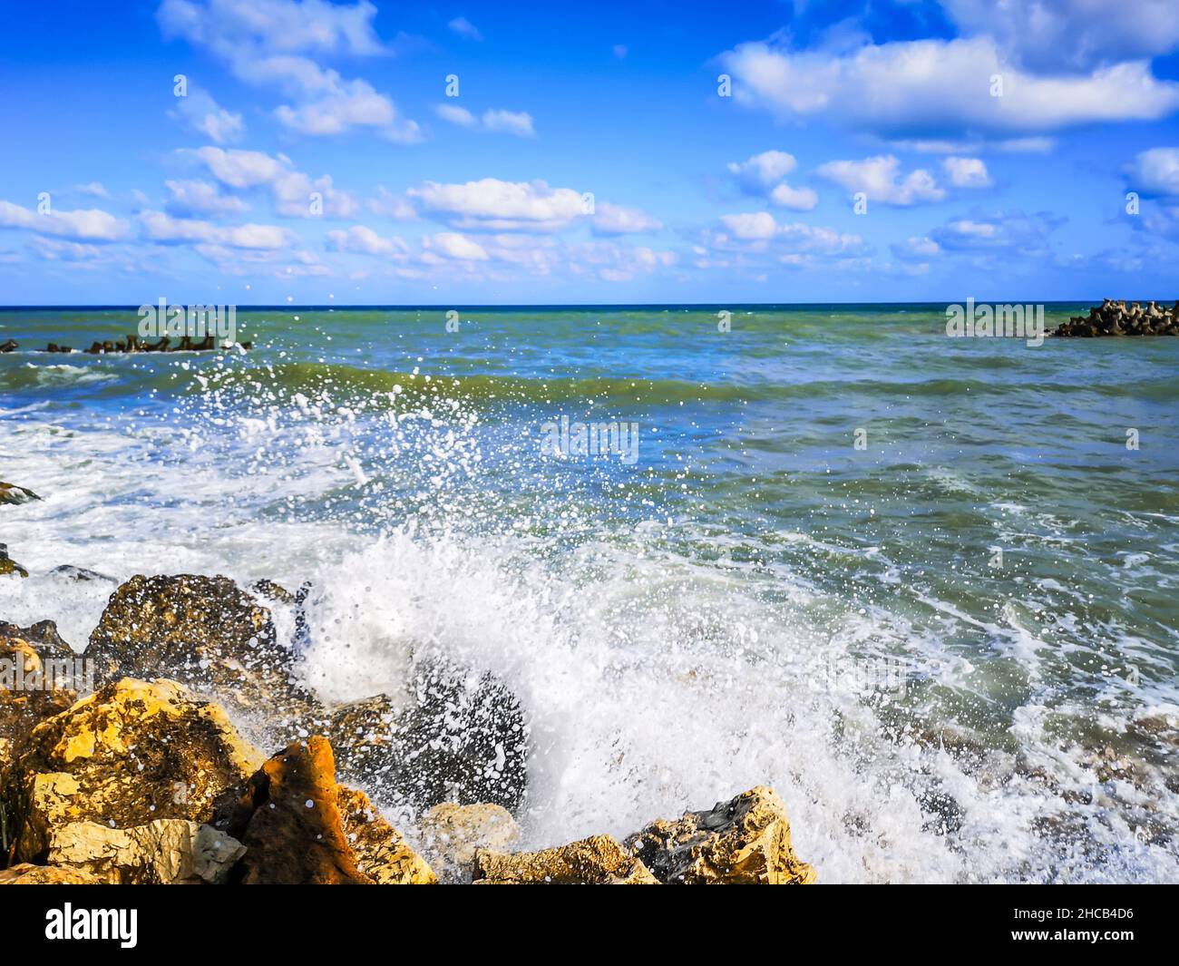 Riva del mare con acqua blu, rocce e cielo estivo mistico Foto Stock