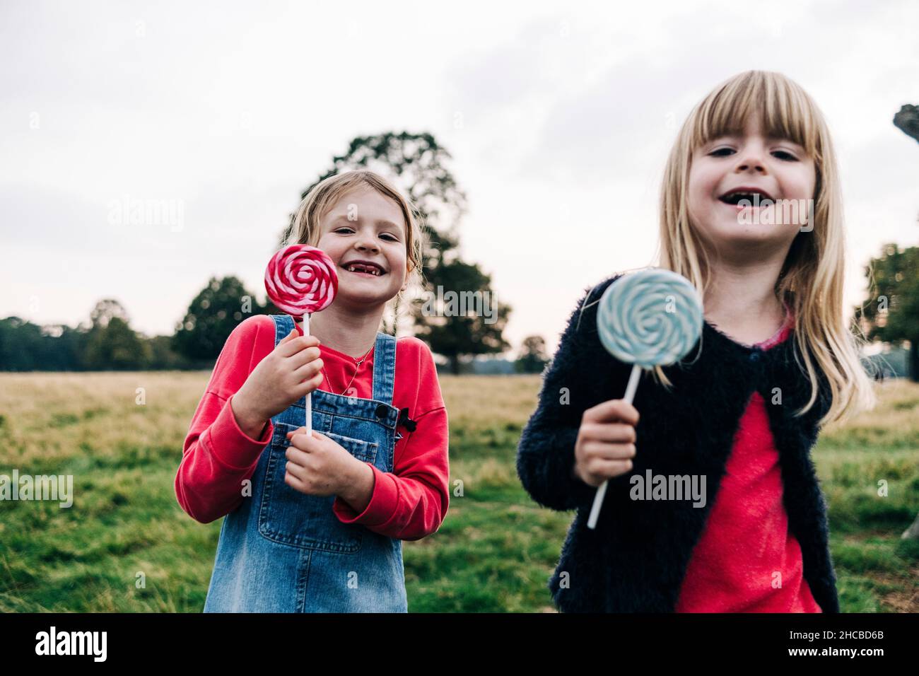 Sorelline felici che tengono lollipops al parco pubblico Foto Stock