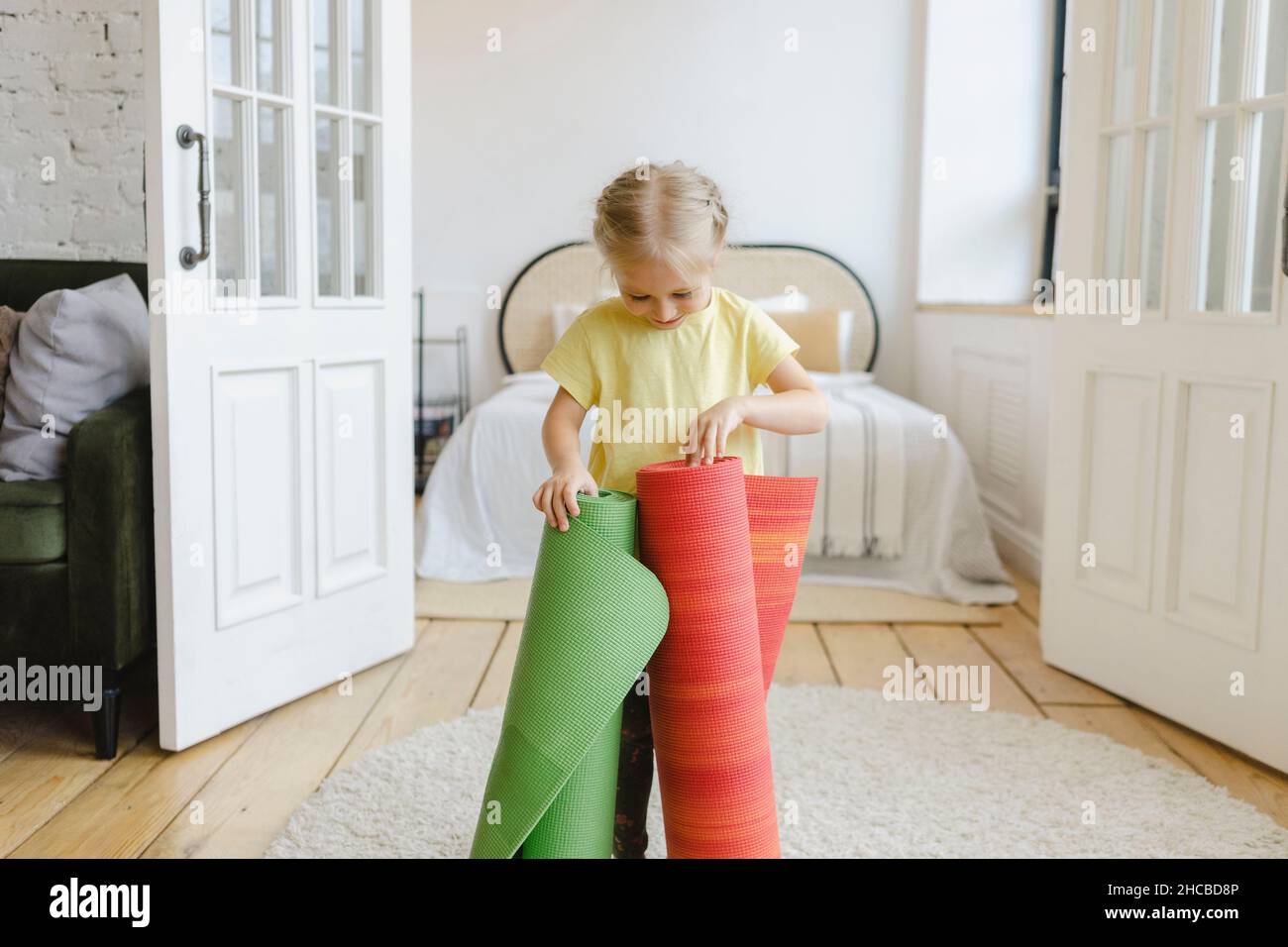 Ragazza che gioca con stuoie da sforzo a casa Foto Stock