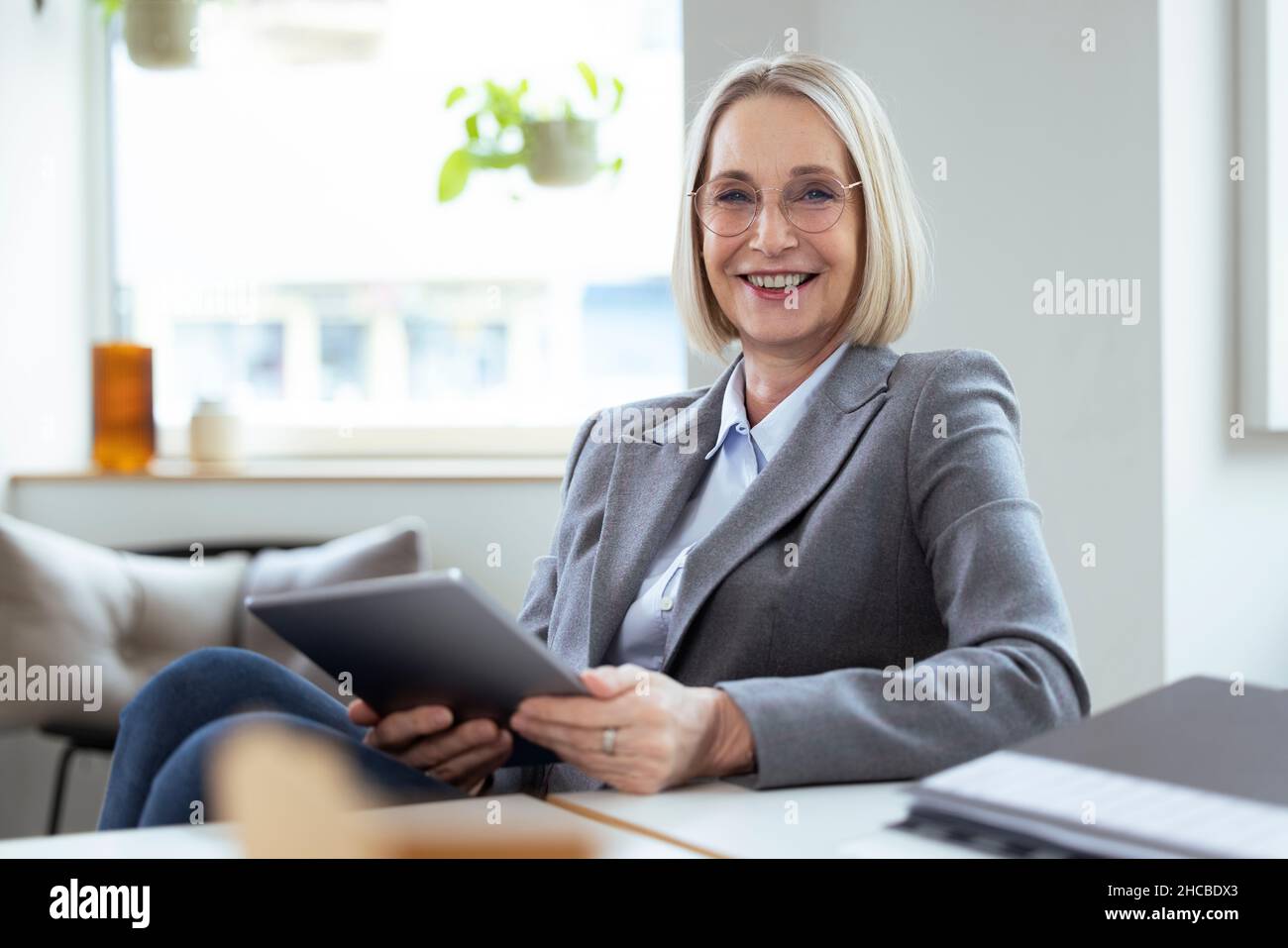 Donna d'affari bionda con tablet PC sul posto di lavoro Foto Stock