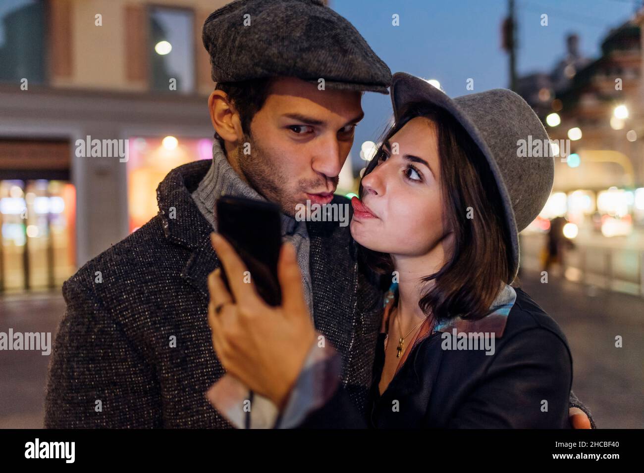 Ragazza e ragazzo facendo volti divertenti mentre si prende selfie attraverso lo smartphone Foto Stock