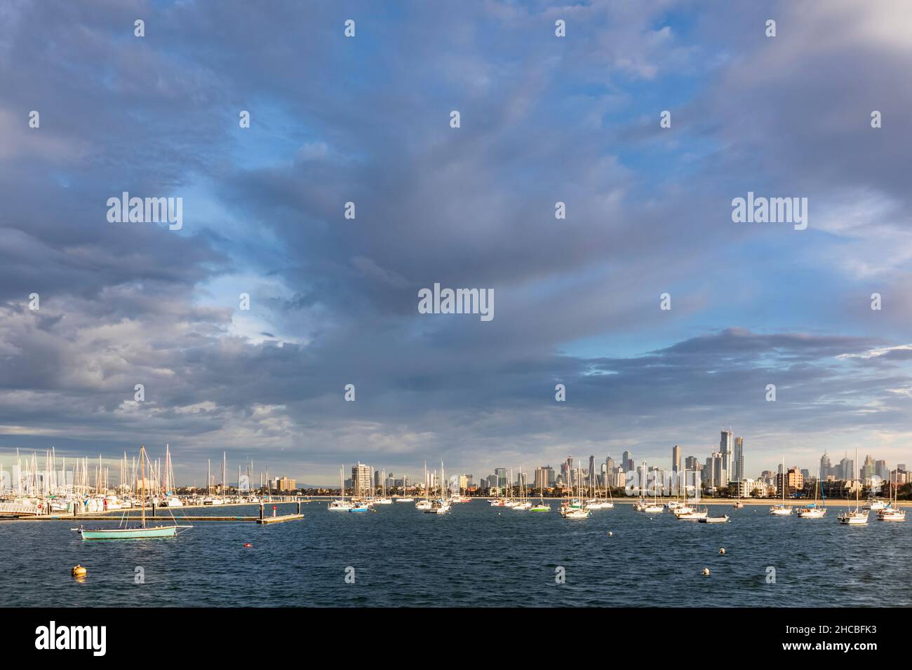 Australia, Victoria, Melbourne, Yachts galleggiano contro lo skyline illuminato della città al tramonto Foto Stock