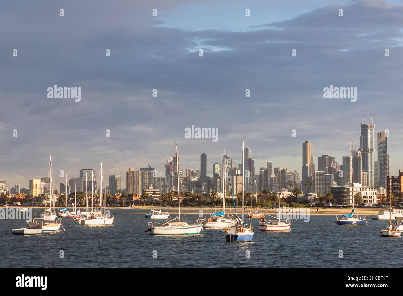 Australia, Victoria, Melbourne, Yachts galleggiano contro lo skyline illuminato della città al tramonto Foto Stock