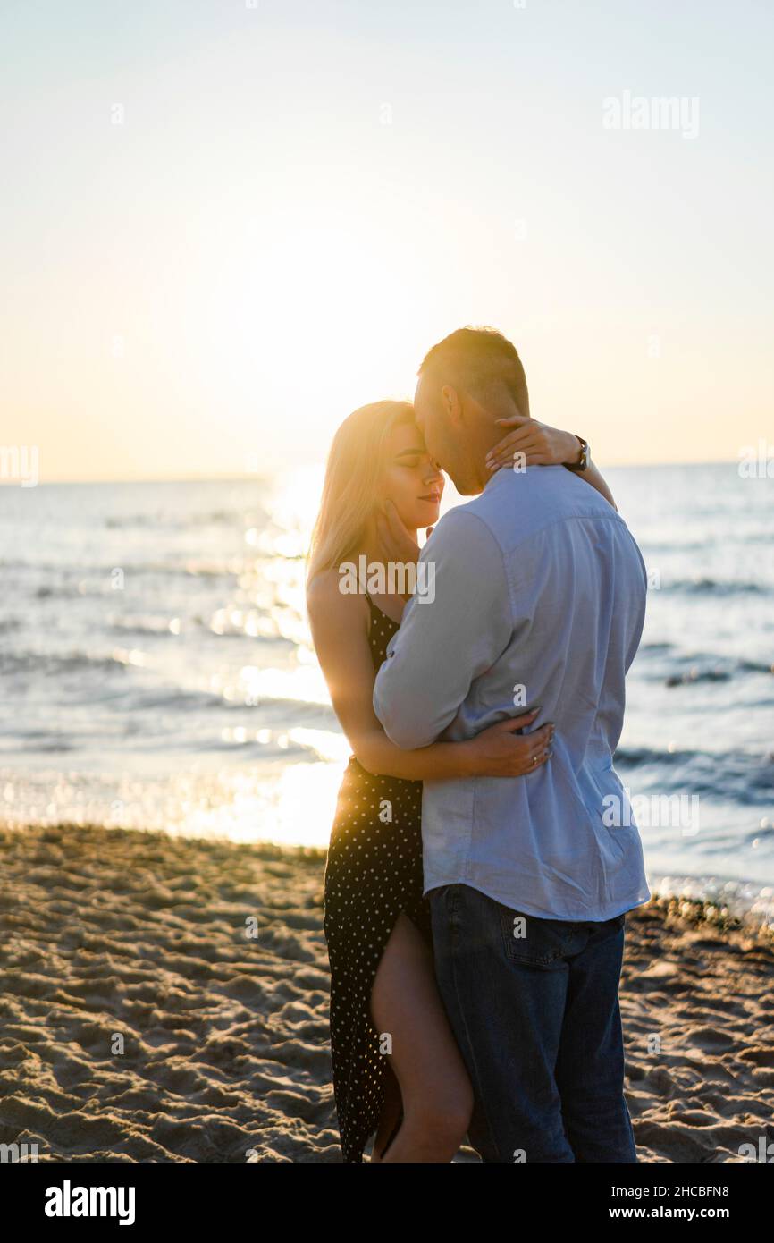 Una giovane coppia amorevole che si abbraccia a vicenda in spiaggia Foto Stock