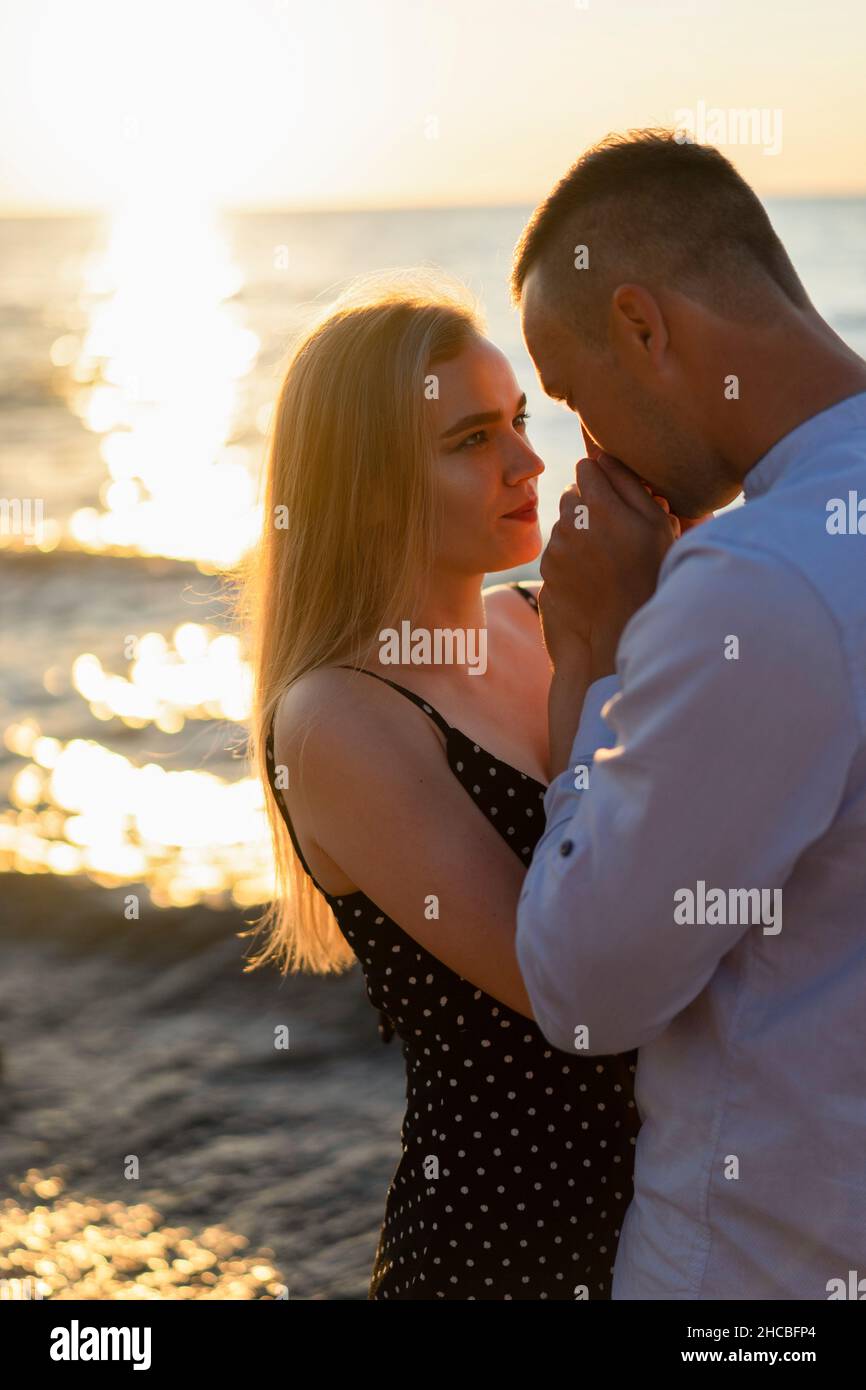 Uomo che tiene e bacia la mano della donna al tramonto Foto Stock